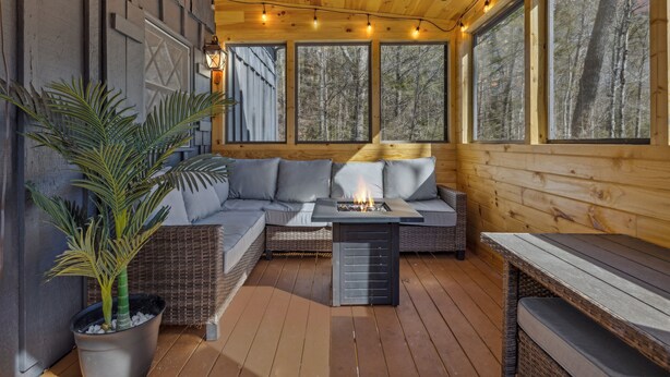 Een houten terras met een bank, een tafel en een vuurkuil.