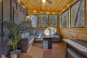 A wooden deck with a sofa, a table, and a fire pit. - High Top Cabin 3 Bedroom Cabin (Sevierville)
