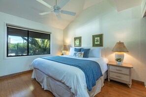 A bedroom with a large bed, two bedside lamps, a nightstand, and a ceiling fan. - Maalaea Surf C10 2 Bedroom Condo (Kihei)