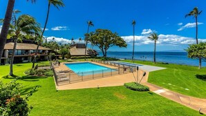 A resort with a swimming pool, palm trees, and a view of the ocean. - Maalaea Surf C10 2 Bedroom Condo (Kihei)