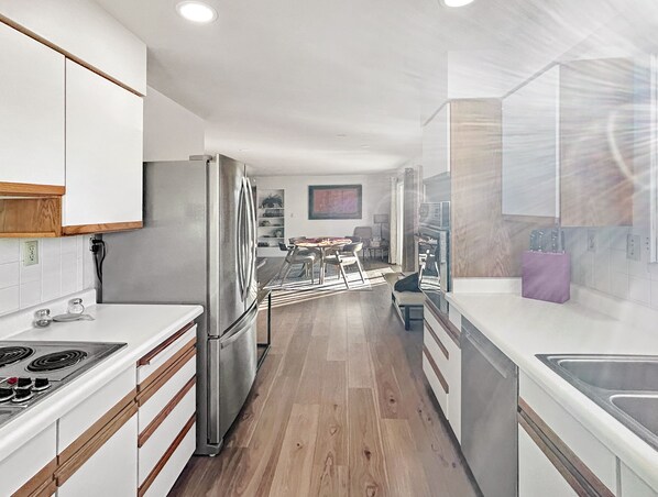 A modern kitchen with white cabinetry, a stainless steel refrigerator, and a gas stove.