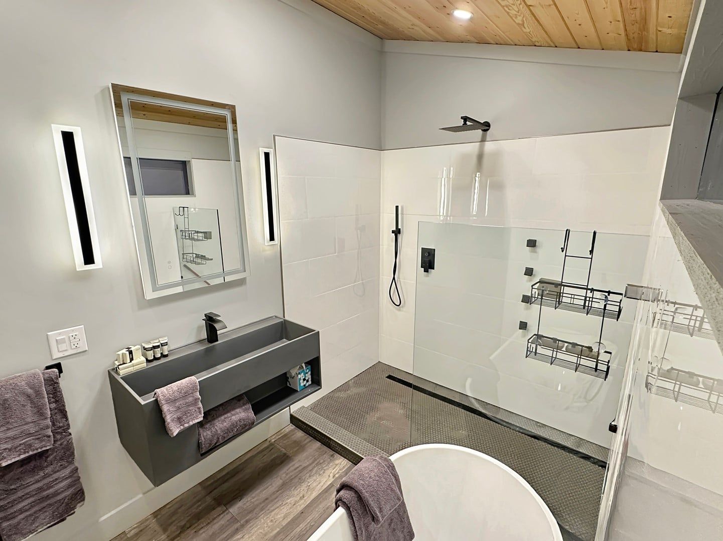 Een moderne badkamer met een douche in een glazen cabine, een wastafel met spiegel en een toilet.
