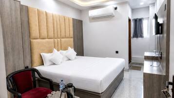 Una habitación de hotel moderna con una cama grande, una silla roja, una mesita con un hervidor de agua y un equipo de aire acondicionado.