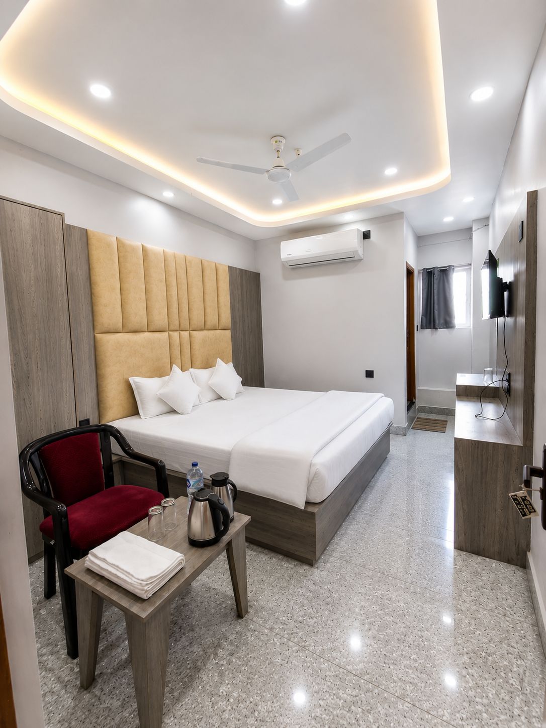 Une chambre d’hôtel moderne équipée d’un lit, d’un bureau, d’une chaise, d’un climatiseur et d’un téléviseur.