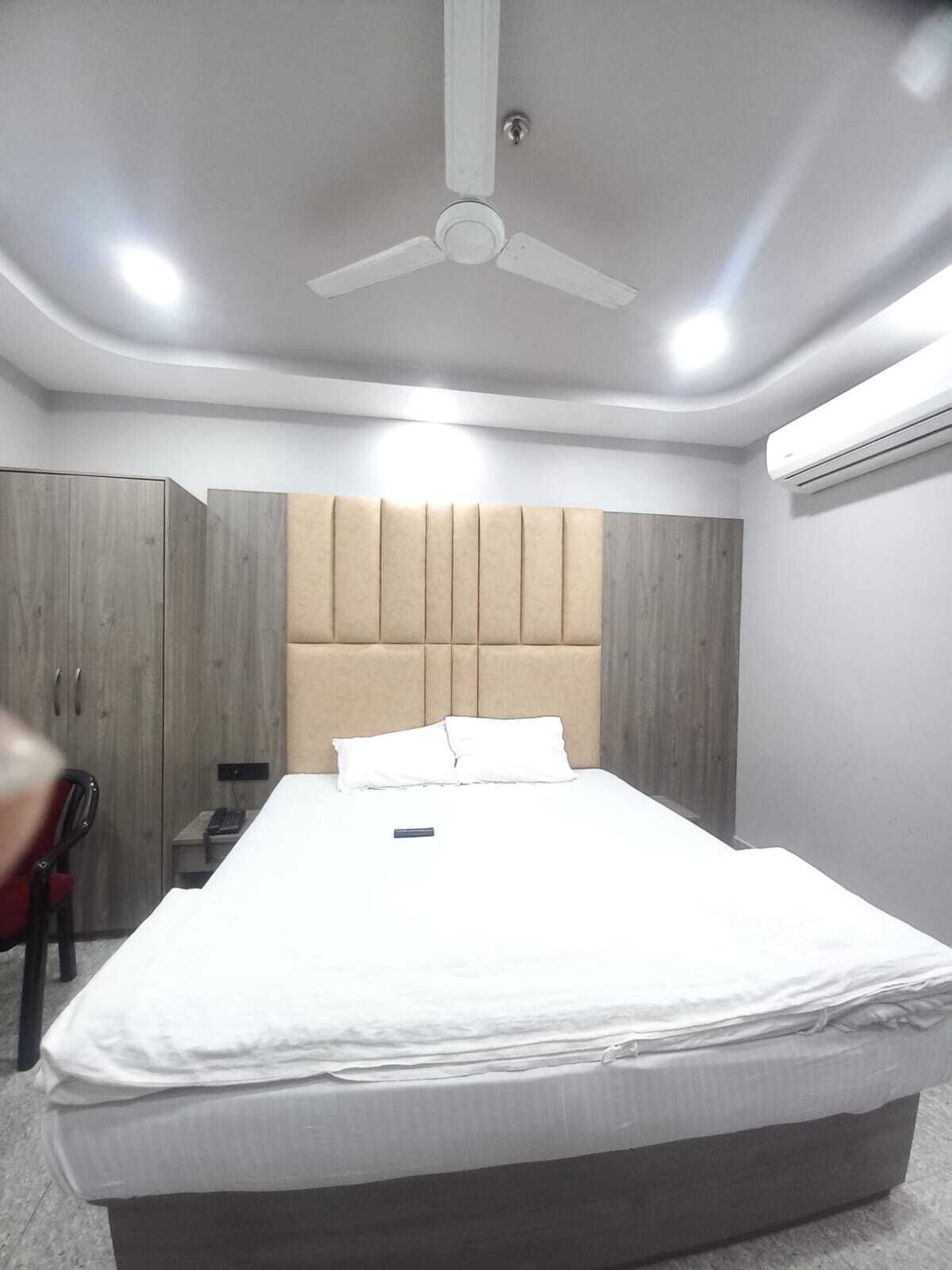 Une chambre à coucher comprenant un lit, un ventilateur de plafond, un appareil de climatisation et une armoire.