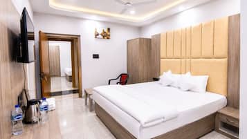 A hotel room with a large bed, a wardrobe, a television, and a ceiling fan.