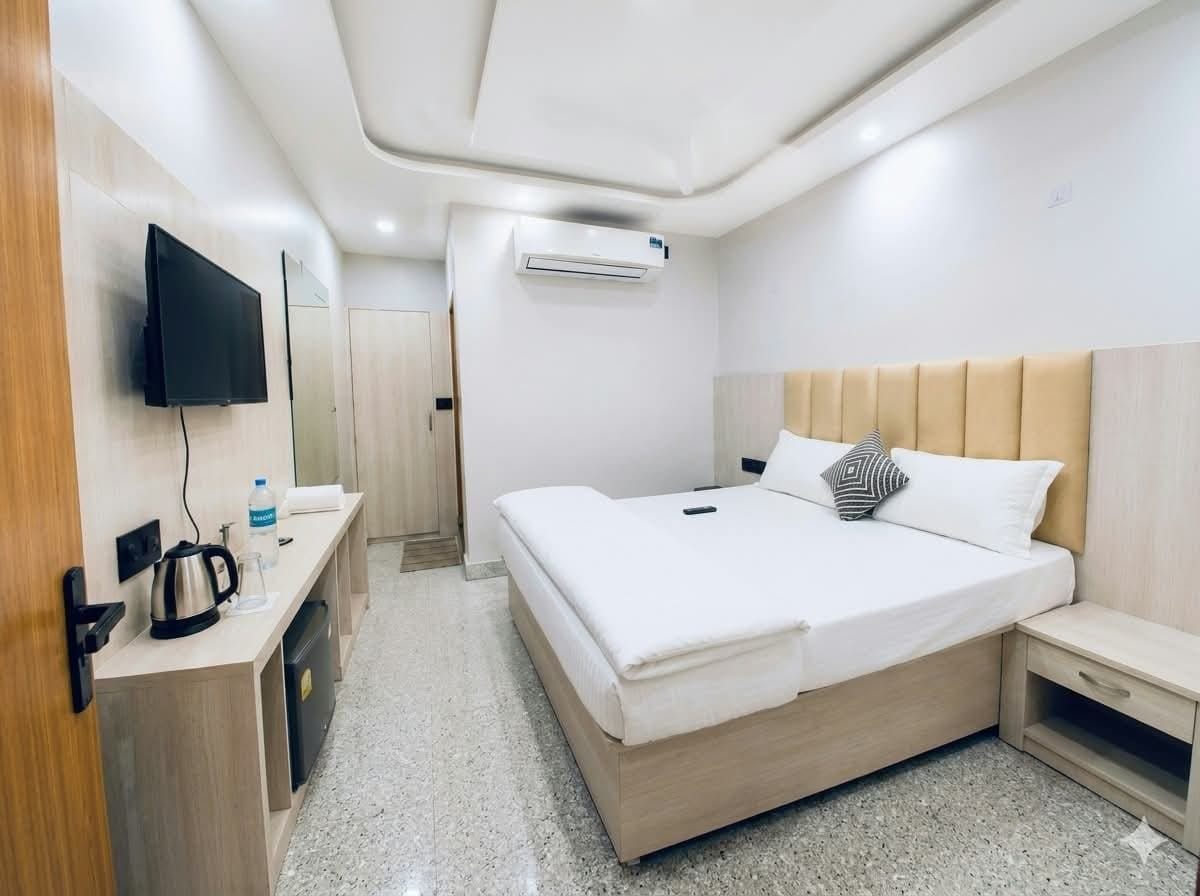 Ein Hotelzimmer mit einem Bett, einem Fernseher, einer Kaffeemaschine und einem kleinen Tisch.