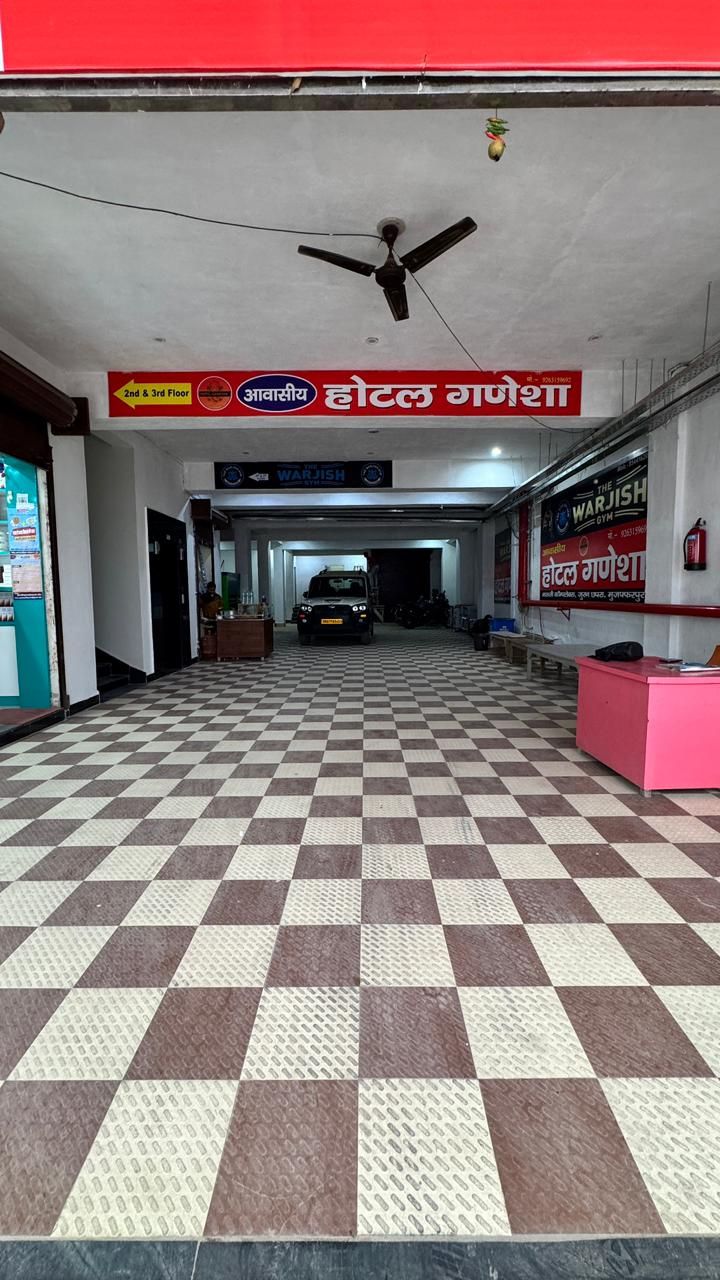 Un pasillo de hotel con suelo a cuadros, un ventilador de techo, indicaciones y un vehículo estacionado.
