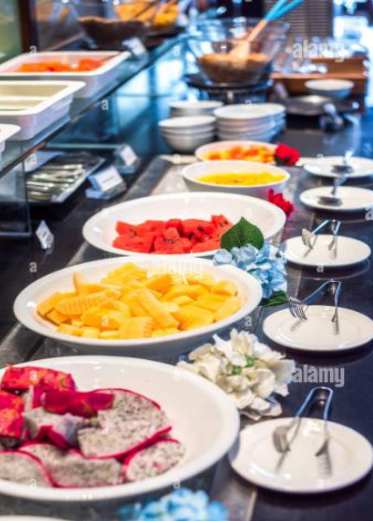Un bufé con diferentes opciones de comida, incluyendo frutas, pasta y una ensalada.