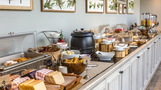 A buffet setup with various food items, including bread, pastries, and a hot pot. - Hotel KHS Landmark Prayagraj - The Boutique Hotel (Prayagraj)