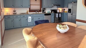 Una cocina moderna con armarios azules, una mesa de comedor de madera y un tazón de bocadillos.