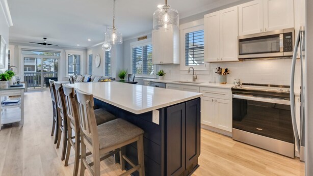 A modern kitchen with a central island, stainless steel appliances, and pendant lighting. - Sweet Serendipity - Close to beach, Greenway, and popular restaurants and bars. (Carolina Beach)
