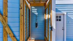 A narrow wooden hallway with a blue exterior wall, a white door, and a small window. - Sweet Serendipity - Close to beach, Greenway, and popular restaurants and bars. (Carolina Beach)