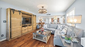 A spacious living room with a large wooden entertainment unit, a grey sofa, and a coffee table. - Discover Gulf and Bay Club Unit F407 in Siesta Key! (Siesta Key)