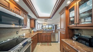 A modern kitchen with wooden cabinets, stainless steel appliances, and a central island. - Discover Gulf and Bay Club Unit F407 in Siesta Key! (Siesta Key)