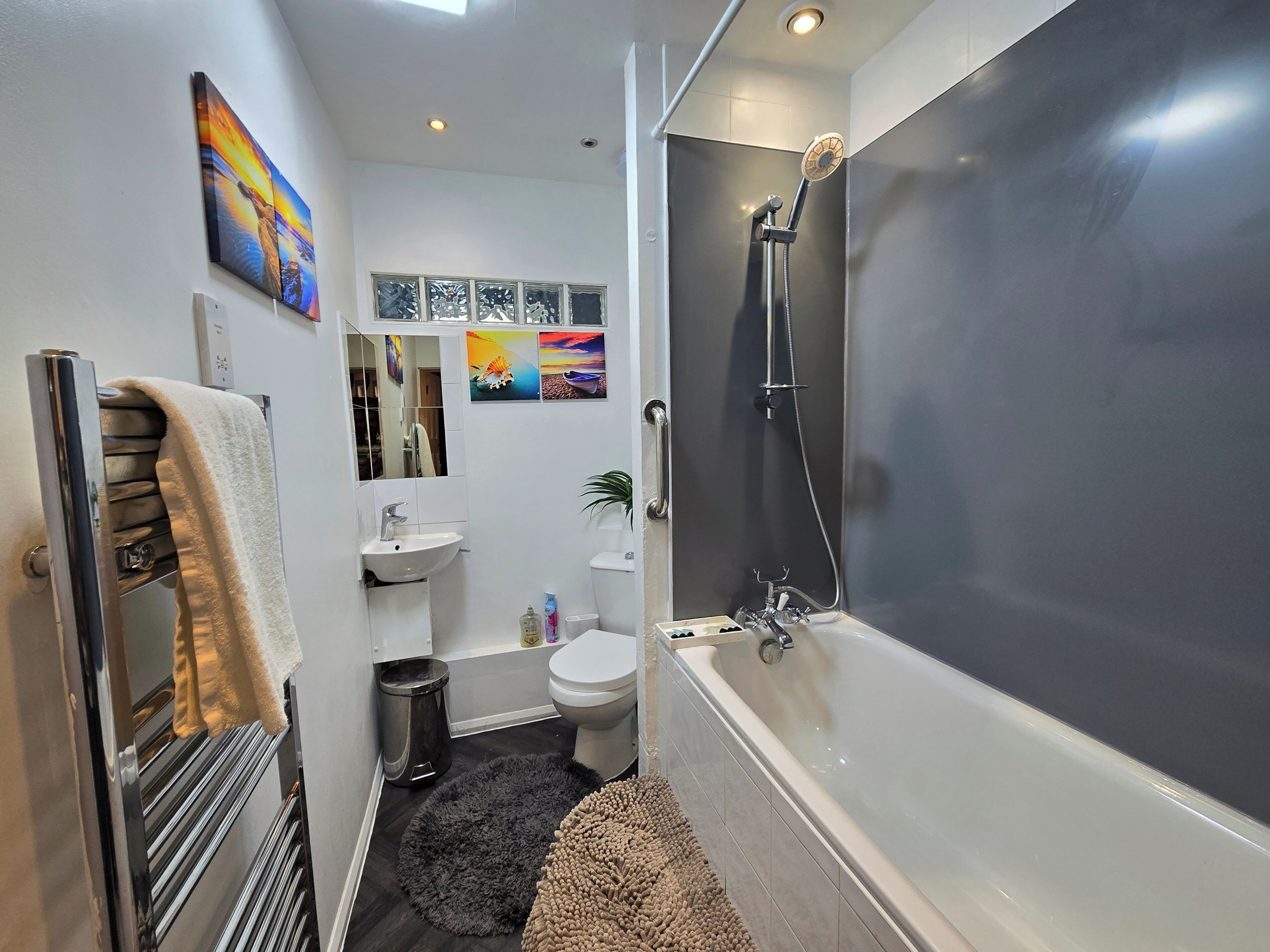 Une salle de bain moderne équipée d’une baignoire, de toilettes, d’un lavabo et d’un porte-serviettes.
