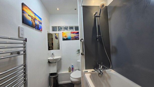 Un baño moderno con bañera, inodoro, lavamanos y un perchero para toallas.