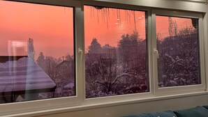 Une pièce dotée de trois fenêtres donnant sur un paysage enneigé au coucher du soleil.
