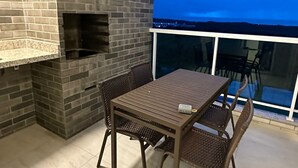 Eine Terrasse mit Kamin aus Ziegelsteinen, einem Tisch mit Stühlen und Blick durch eine Glastür.