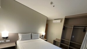 Ein Hotelzimmer mit Bett, Nachttischlampen, einem Kleiderschrank und einer Klimaanlage.