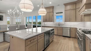 A spacious kitchen with a large island, modern appliances, and a view to the outdoors. - Tyson’s Corner: Luxe Marshfront Retreat w/ Pool (Murrells Inlet)
