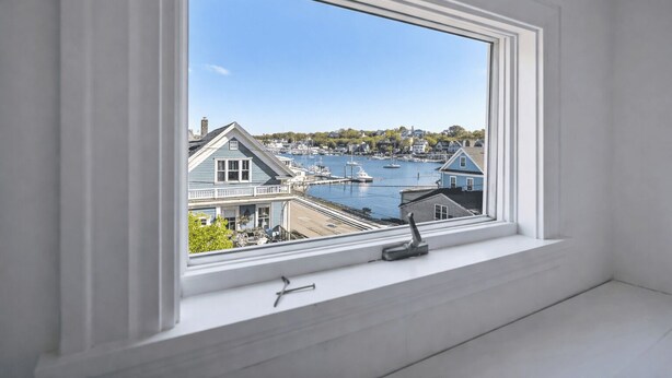 A room with a large window overlooking a marina with boats and houses. - Painter's Perch: Rocky Neck (Gloucester)