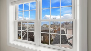 A window with multiple panes offering a view of neighboring houses and a clear sky. - Portside Overlook: Downtown Rockport Penthouse with stunning views (Rockport)
