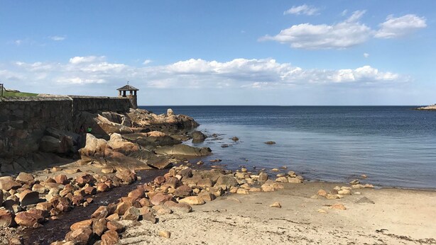 Una costa rocosa con una pequeña estructura de piedra y una vista despejada del mar.