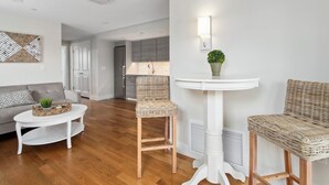 Una sala moderna con un sofá blanco, una mesa de centro redonda y dos sillas de mimbre.