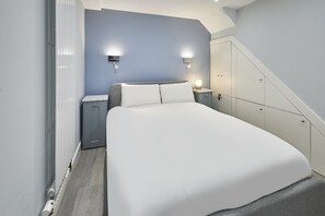 A modern bedroom with a large bed, two bedside tables, a wardrobe, and a staircase. - Host & Stay | Harrow Bothy (Tweedmouth)