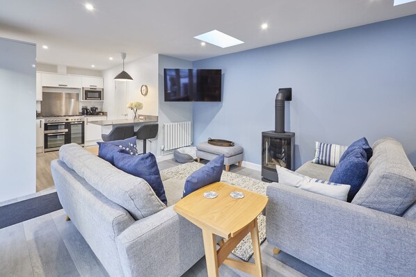 A modern living room with grey sofas, a wooden coffee table, and a TV mounted on the wall. - Host & Stay | Harrow Bothy (Tweedmouth)