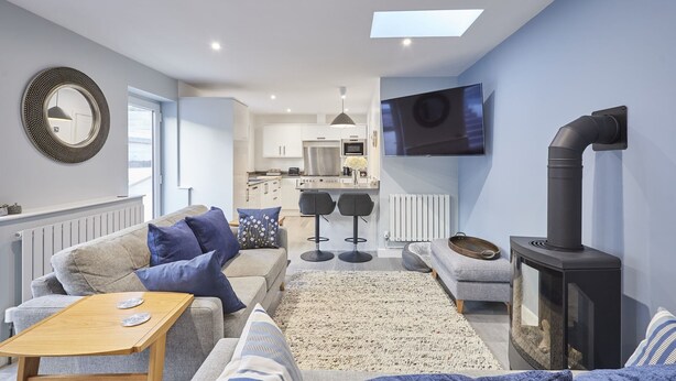 A modern living room with a sofa, a coffee table, a TV, and a fireplace. - Host & Stay | Harrow Bothy (Tweedmouth)