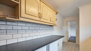 A kitchen with light wooden cabinets, white subway tiles, and a black countertop. - Host & Stay | Joffre Avenue (Castleford)
