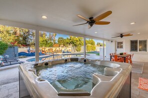 Un jacuzzi con vistas a un jardín ajardinado y una piscina.
