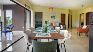 Un comedor con una mesa de madera dispuesta para cuatro personas, sillas alrededor y vistas al exterior a través de un ventanal corredero.