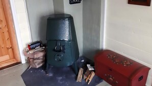 A room with a green stove, a red chest, and a black decorative wall piece. - 5 Person Holiday Home in Lyngdal (Lyngdal)