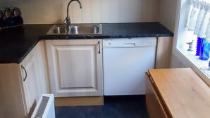 A compact kitchen with a dishwasher, a sink, and a small window. - 5 Person Holiday Home in Lyngdal (Lyngdal)