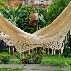 Relax in a serene garden oasis, where a hammock awaits amidst lush greenery and vibrant blooms.