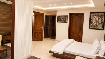 A bedroom with a bed, a sofa, a wooden cabinet, and a door leading to another room.