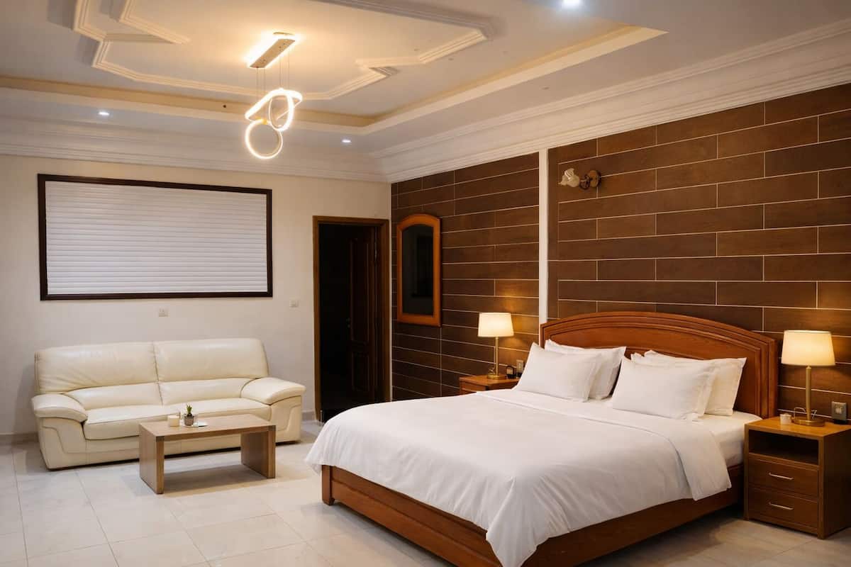 A hotel room with a bed, a sofa, a nightstand, and a wall-mounted mirror.