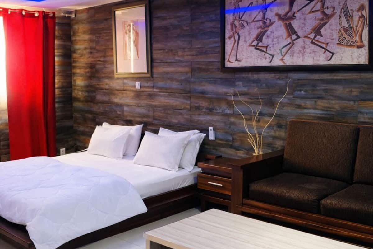 A modern bedroom with a bed, a sofa, a coffee table, and a wall with artwork.