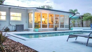 A modern house with a swimming pool, large windows, and a covered patio area. - Private Pool Villa | 5 Min to Disney & Universal (Orlando)