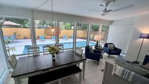 A dining area with a table, chairs, and a view of a backyard pool. - Private Pool Villa | 5 Min to Disney & Universal (Orlando)