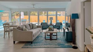 A spacious living room with a sofa, chairs, a coffee table, and a dining area. - Private Pool Villa | 5 Min to Disney & Universal (Orlando)