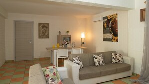 Un salon comprenant un canapé, une table à manger avec des chaises, une porte et un mur orné d’œuvres d’art.
