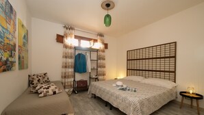 Une chambre avec deux lits, une armoire, un miroir et une lampe suspendue verte.