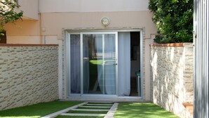 Un petit jardin clos, avec une porte-fenêtre coulissante donnant sur un patio.