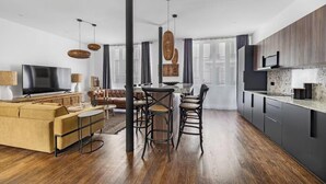 Un salon moderne avec un canapé, un téléviseur et un coin repas comprenant des chaises.