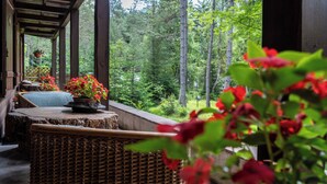 A covered porch with wicker furniture and potted plants. - B&B Villa La Bercia (Marebbe)