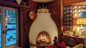 A cozy room with a fireplace, wooden walls, and a collection of plates on the wall. - B&B Villa La Bercia (Marebbe)